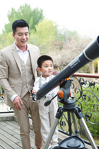 父亲和儿子在阳台使用天文望远镜