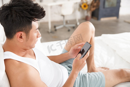 青年男人在卧室玩手机