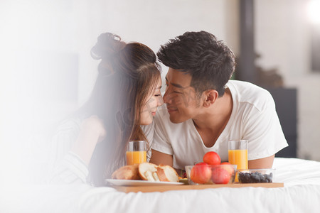 清新简约彩色摄影照片_青年情侣在床上吃早餐