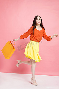 618粉色背景摄影照片_时尚年轻女人拿着购物袋