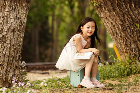 坐在草地摄影照片_可爱的小女孩在户外