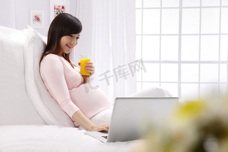 科技新生活摄影照片_孕妇坐在床上看电脑