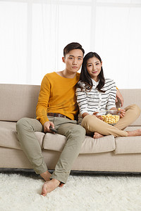 青年情侣坐着沙发上看电视
