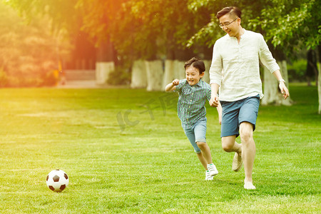 生活环境摄影照片_快乐父子在草地上踢足球