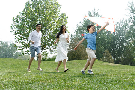 亚洲男孩摄影照片_一家三口在草地上放风筝
