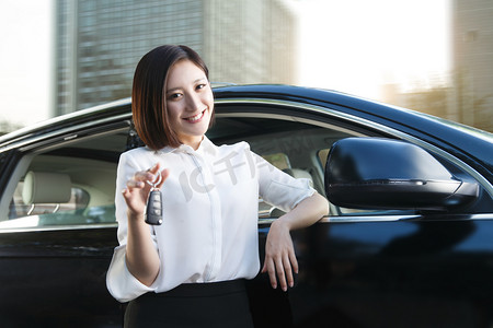 销售主管摄影照片_青年女人拿着车钥匙站在汽车旁边