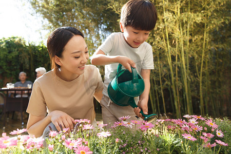竹林景象摄影照片_母亲和儿子在花园里浇花