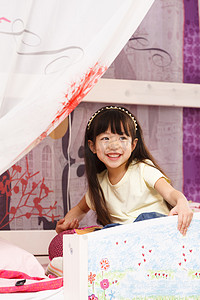 窗帘卡通摄影照片_可爱的小女孩在床上玩耍