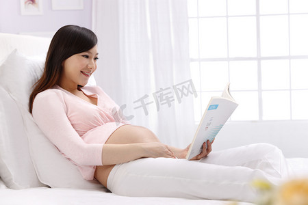 孕妇坐在床上看书