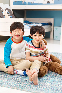 室内家居摄影照片_两个男孩坐在卧室的地毯上