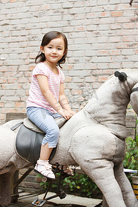 可爱的小女孩在骑摇摆木马