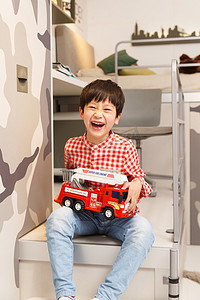 拿玩具汽车的男孩摄影照片_小男孩在卧室里拿着玩具车