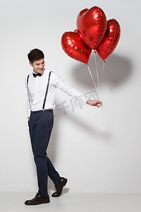 彩色爱心背景摄影照片_青年男人拿着心形气球