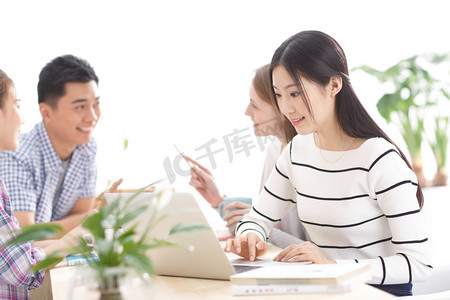 白色桌子桌子摄影照片_年轻的大学生在使用电脑