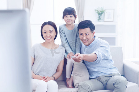 亚洲家庭亲子摄影照片_幸福的一家三口在客厅看电视