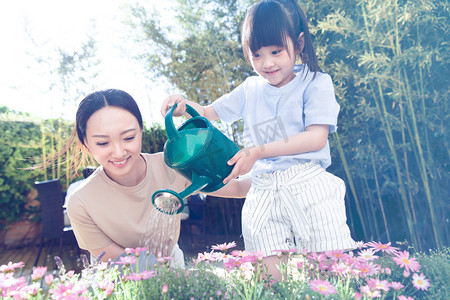 植树节人摄影照片_年轻的母亲和女儿在浇花