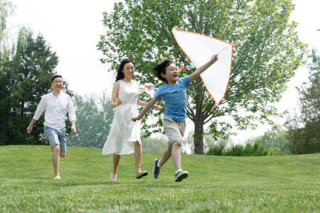 放暑假摄影照片_一家三口在草地上放风筝