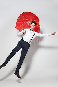 彩色爱心背景摄影照片_青年男人拿着心形红雨伞