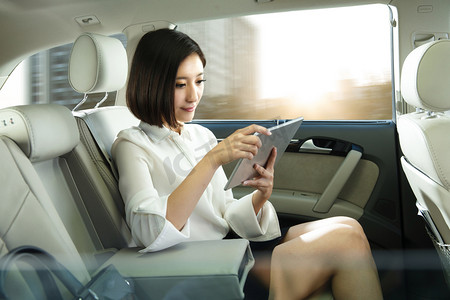 一个小学生卡通摄影照片_青年女人坐在汽车里看平板电脑