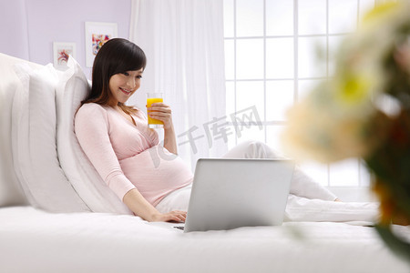 孕妇坐在床上看电脑