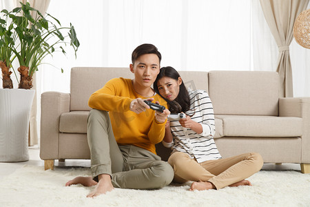 青年情侣坐着沙发上玩游戏