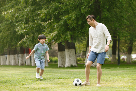 保护草地摄影照片_快乐父子在草地上踢足球