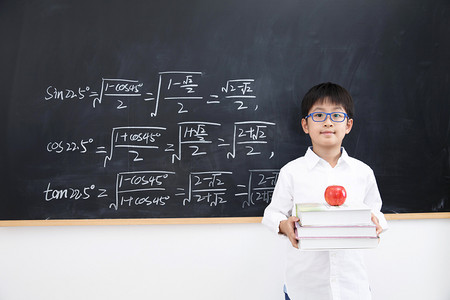 数学思考摄影照片_小学男生站在黑板前