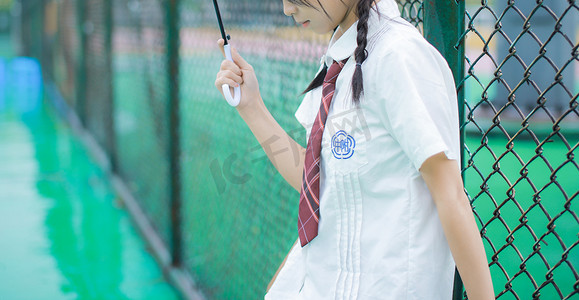 难过的女孩摄影照片_雨天操场上的女子摄影图配图