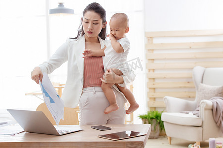 母子年轻女人摄影照片_年轻妈妈抱着孩子在家办公