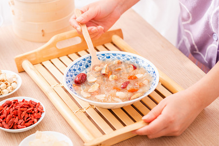 美食白天银耳莲子羹木桌拿摄影图配图