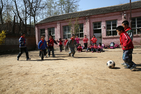 彩色愚人节快乐字摄影照片_乡村小学生在学校里踢足球