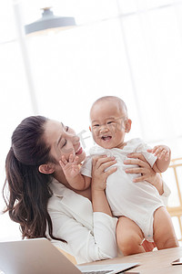 弯弯的月亮的图片摄影照片_年轻妈妈抱着孩子在家办公