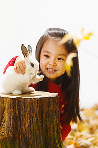 秋天温馨背景摄影照片_小女孩和小兔子