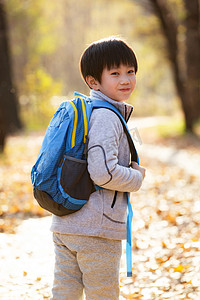 背书包书包摄影照片_秋天户外小路上背书包的小男孩