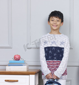 young asian boy smiling standing beside book desk