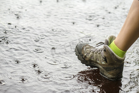 人在徒步旅行靴走在雨中的水