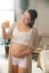 创意橙汁海报摄影照片_孕妇正在喝果汁