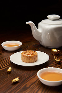 中秋中秋节摄影照片_传统的月饼与茶杯, 锅和金锭隔离在黑色