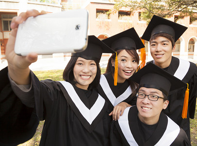 bachelor摄影照片_Group of graduates  taking picture with cell phone