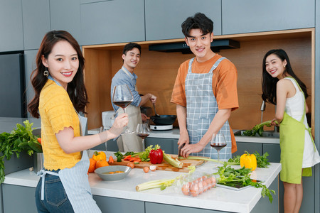 聚会喝酒摄影照片_快乐的年轻人边做饭边喝红酒