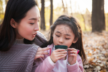 秋天户外幸福的母女在喝水