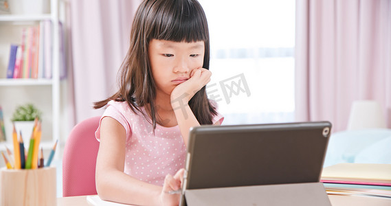 上吉上上吉摄影照片_使用平板电脑快乐地在网上上课时，亚洲女生感到很无聊