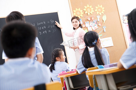 举手课堂摄影照片_女教师和小学生们在教室里