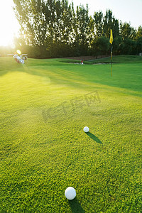 高尔夫球包摄影照片_阳光下的高尔夫球场与球