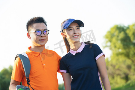 快乐的青年人背着高尔夫球包在球场