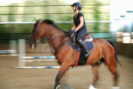 女子骑马摄影照片_马场上骑马奔跑的年轻女子