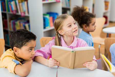 selective focus of cute kid holding book near african american children 