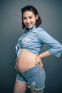 蓝色背景人物图摄影照片_穿着时尚的孕妇