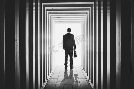 恐怖走廊摄影照片_生意人在线形状的走廊和迷茫离开未知的明亮的门 .