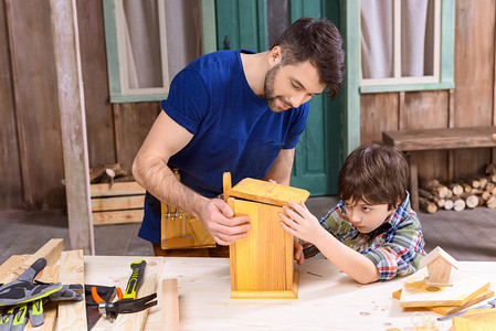 planks摄影照片_Father and son making birdhouse 